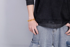 Macro shot of polished gold-toned stainless steel beaded bracelet worn by a model