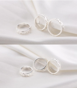Detail view of silver stainless steel rings with hammered texture on white silk fabric