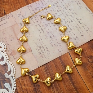 Close-up of golden stainless steel heart chain necklace on vintage letter paper