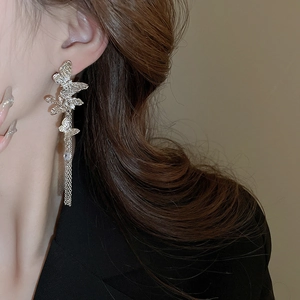 Close-up of elegant silver butterfly tassel earrings featuring layered metallic chains