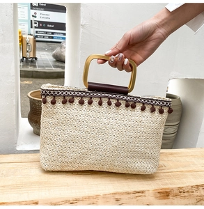 Detail of woven straw tote with brown tassel fringe and gold metal handles
