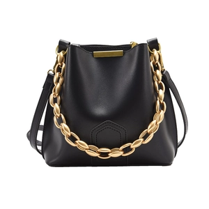 Minimalist black leather bucket bag with a stylish chunky gold chain and strap