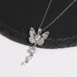 Détail d'un collier pendentif papillon en argent avec pompons en zircon sur roche sombre