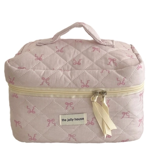Pink quilted makeup bag with bow patterns, top handle, and secure double zipper closure