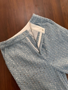 Détail de pantalon bleu clair à paillettes avec fermeture éclair argentée et crochet