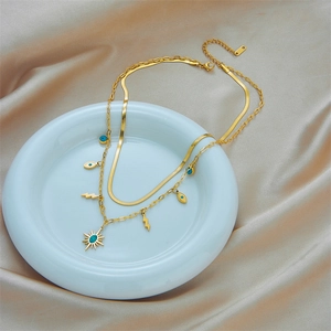 Gold layered necklace with turquoise evil eye and lightning pendants on silk background