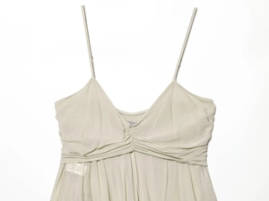 Detail of light gray silk dress with thin straps, V-neck, and delicate pleated texture