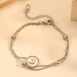 Detailed macro of silver double-layer snake chain bracelet with moon charm and steel beads