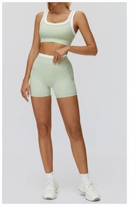 Close-up of sage green yoga set with white contrast piping and high-waist shorts