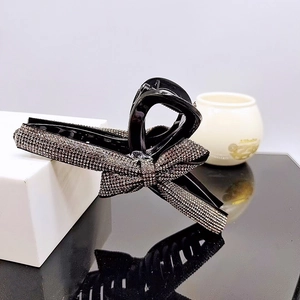 Close-up of a sparkling black shark hair claw clip with a rhinestone bow design detail