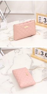 Pink quilted crossbody bag with gold chain strap and metal plate on marble table