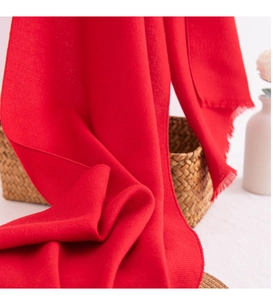 Detail of red festive scarf featuring soft cashmere texture and delicate fringe tassels