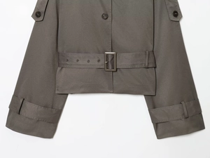 Detailed close-up of dark grey trench coat waist belt and textured twill fabric