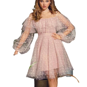Detail of pink polka dot mesh dress with ruffles and lantern sleeves on white background