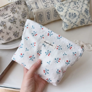 Detailed macro view of small floral cotton pouches with metallic zipper and fabric label