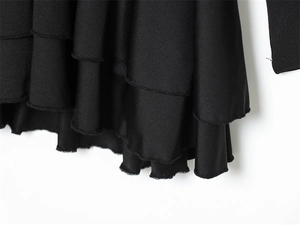 Macro detail of black ruffled hem design with multi-layered fabric and precision stitching