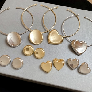 Flat lay of gold and silver heart and oval stud earring and necklace jewelry set