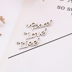 Gros plan de pendentifs polis Peace, Love et Like en acier inoxydable pour création de bijoux