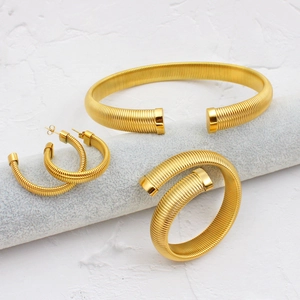 Détail d'un ensemble de bijoux dorés à côtes comprenant bracelet, créoles et bague