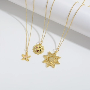 Golden pendant necklaces with starfish, sun medal and star charms on white stands