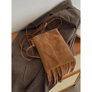 Close-up of brown suede tassel crossbody bag styled on a vintage brown plaid blazer