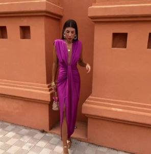 Détail d'une robe en satin fuchsia avec décolleté en V, plis à la taille et fente haute