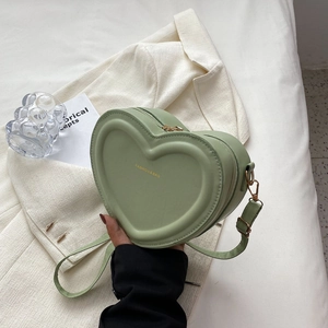 Dettaglio borsa a cuore verde in pelle con cerniera dorata e scritta di moda elegante