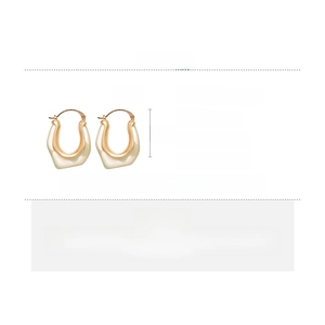 Detail of U-shaped gold copper and cream resin earrings showing size and texture
