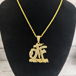 Vue rapprochée du pendentif hip hop doré orné de cristaux sur un support noir