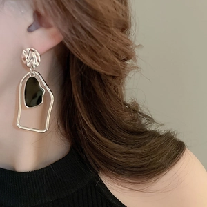 Detail of silver geometric earrings with black asymmetric resin inlay on female model