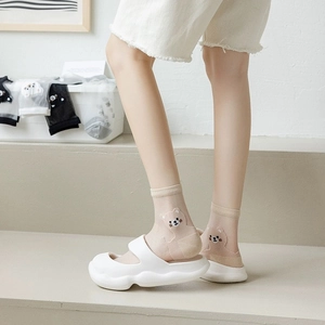 Detail of sheer glass silk socks with cute bear pattern in creamy beige tones