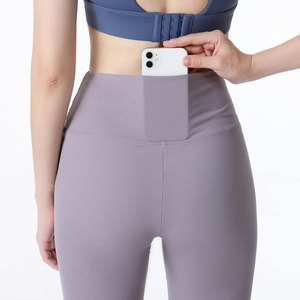 High-waisted purple yoga flared pants with a back pocket holding a smartphone