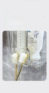Close-up of wall-mounted clear toothbrush holder with dual slots and gold accents