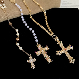 Detailed macro view of retro cross necklaces with pearls and colorful gemstones on velvet