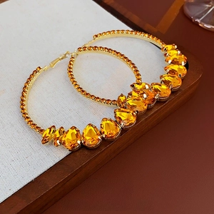 Luxurious gold hoop earrings featuring amber teardrop crystals and sparkling rhinestones