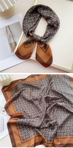 Détail d'un foulard en soie marron à motifs géométriques, noué en nœud et posé à plat