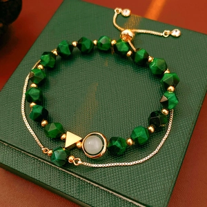 Detail of faceted green beads with golden hardware on a textured emerald gift box