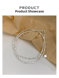 Detail of silver faceted bead necklace with lobster clasp and heart charm on paper