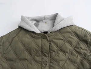 Detail of olive green quilted jacket featuring gray hood and diamond stitching texture