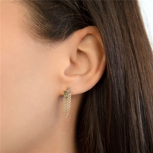 Macro shot of silver tassel earrings with green and white rectangular crystals on ear