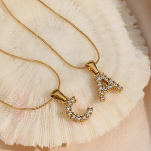 Macro detail of 18K gold plated snake chain with sparkling zircon A and C initial pendants