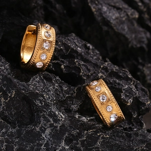 Macro shot of 18K gold plated hoop earrings with shimmering crystals on dark rock background