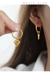 Detailed close-up of gold hollow heart pendant earrings on a model for daily wear