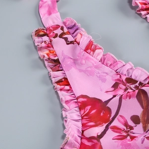 Macro shot of red floral print on pink fabric with ruffled hem detailing and fine stitching