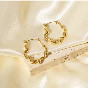 Detailed view of irregular wavy 18K gold earrings with textured dots on premium silk fabric