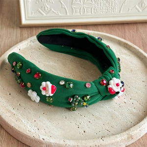 Detail of green knotted Christmas headband with Santa, trees and colorful rhinestones