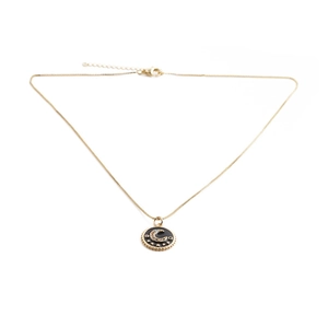 Detail of gold moon and stars pendant with black enamel on a delicate necklace chain