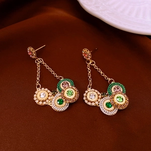 Detailed shot of vintage gold earrings featuring colorful stones on dark fabric