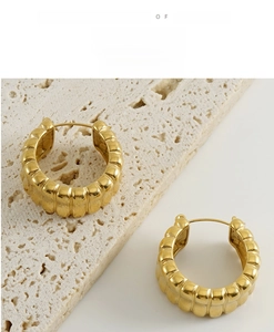 Detailed macro view of U-shaped golden textured metal earrings on stone display