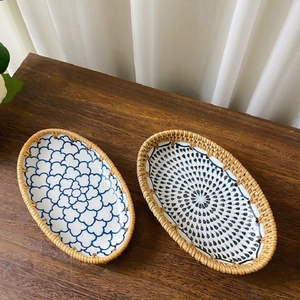 Top view of two oval ceramic fruit trays with blue floral patterns and rattan woven edges